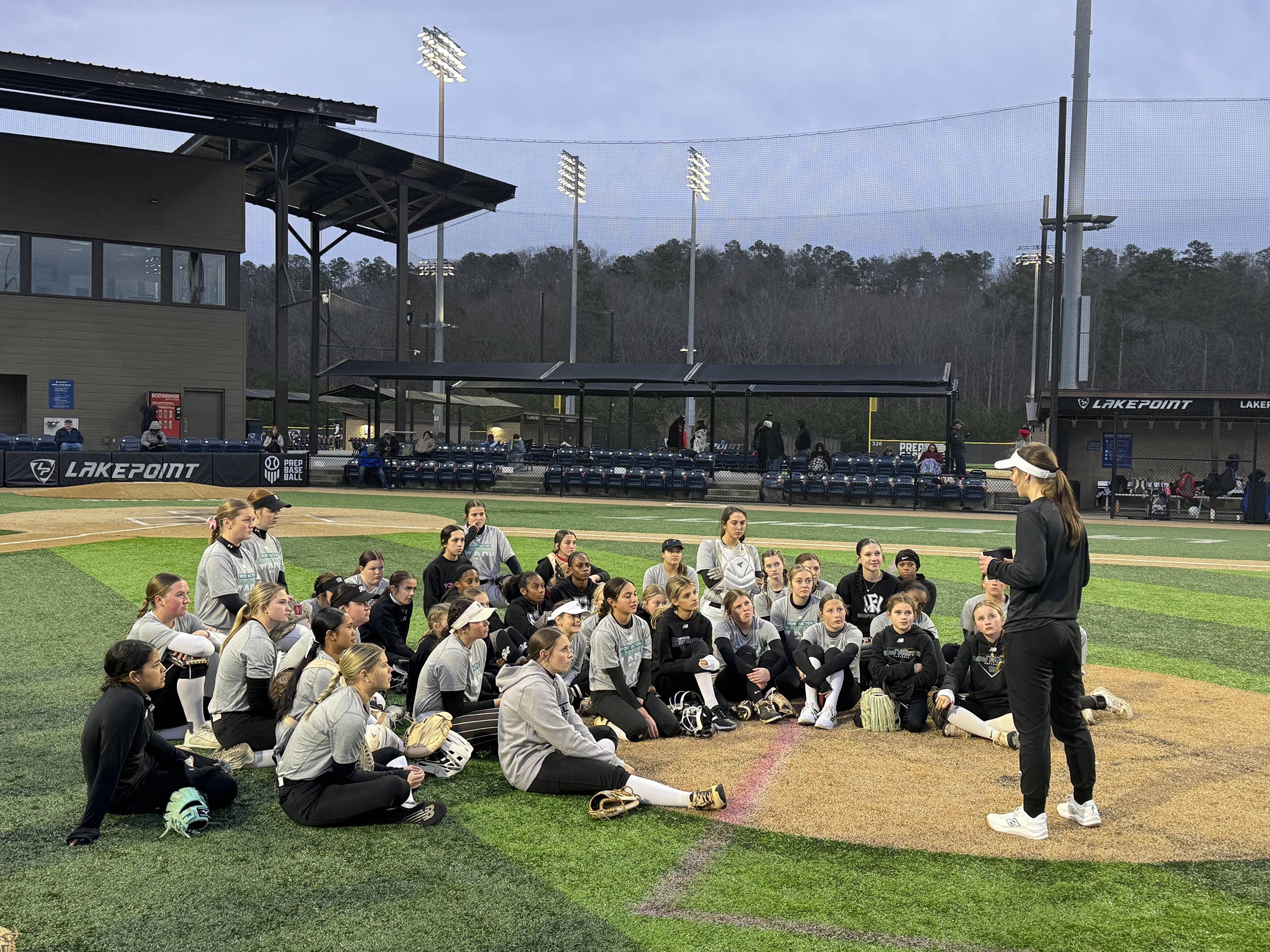 Kelsey O'Connor speaking to a softball team on the field